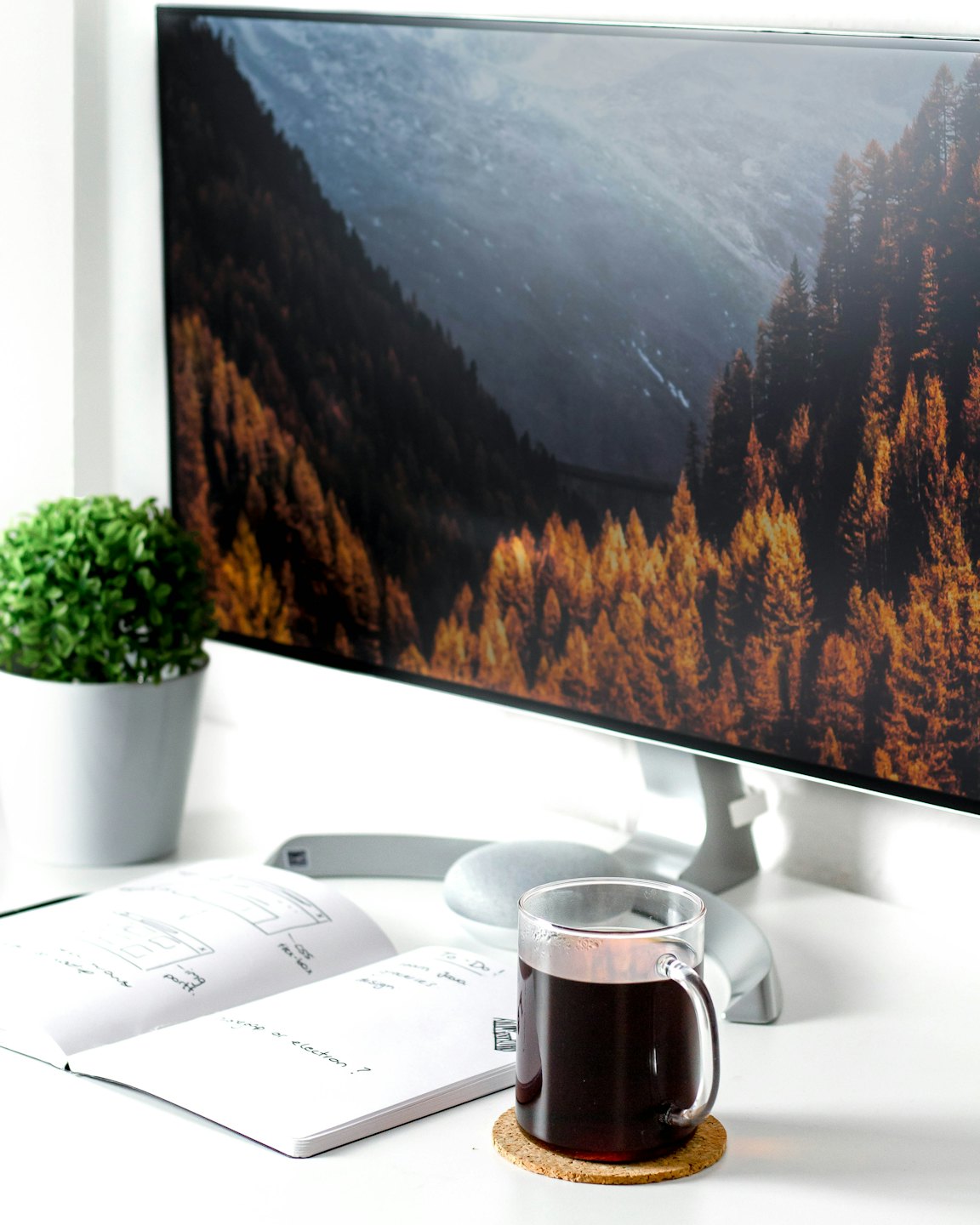 Clean home office desk with computer monitor and notebook.